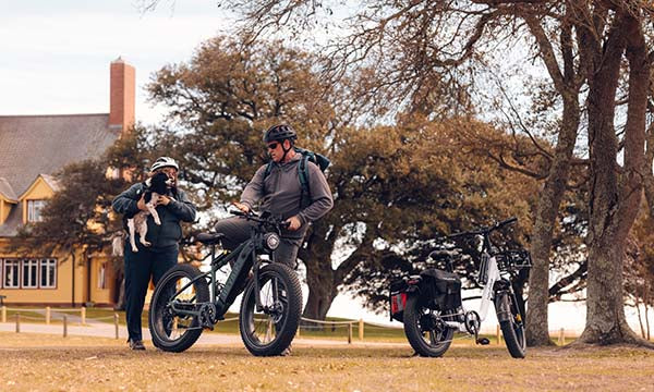 A woman and a man are riding a Brawn fat tire bike with their dog