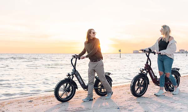 A couple pushing big tires electric bikes on the beach