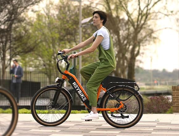 a woman is riding her orange Cityrun ebike