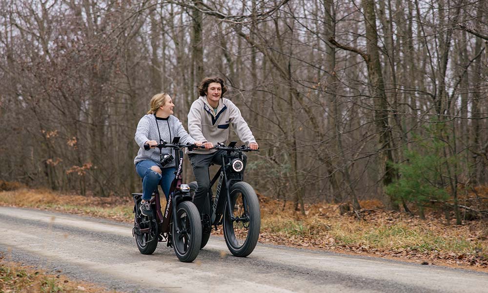 a man and woman are riding Heybike fat tire e-bikes on the trail