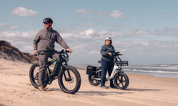 Two heavy riders are riding a fat tire e-bike on the beach