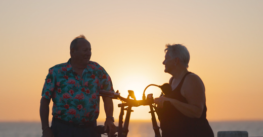 An old couple enjoys riding a fat tire e-bike on the beach.